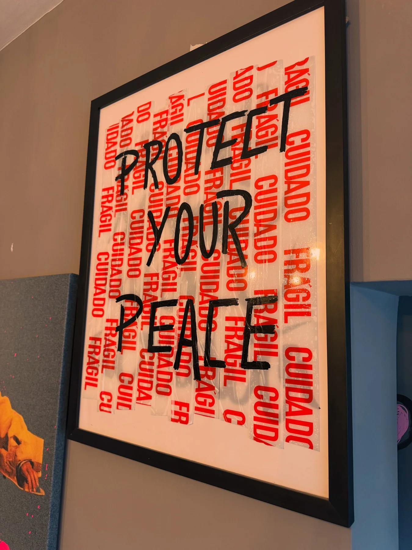 Quadro de moldura preta com fita de frágil vermelha ao fundo e a frase protect your peace em preto (foto 2)