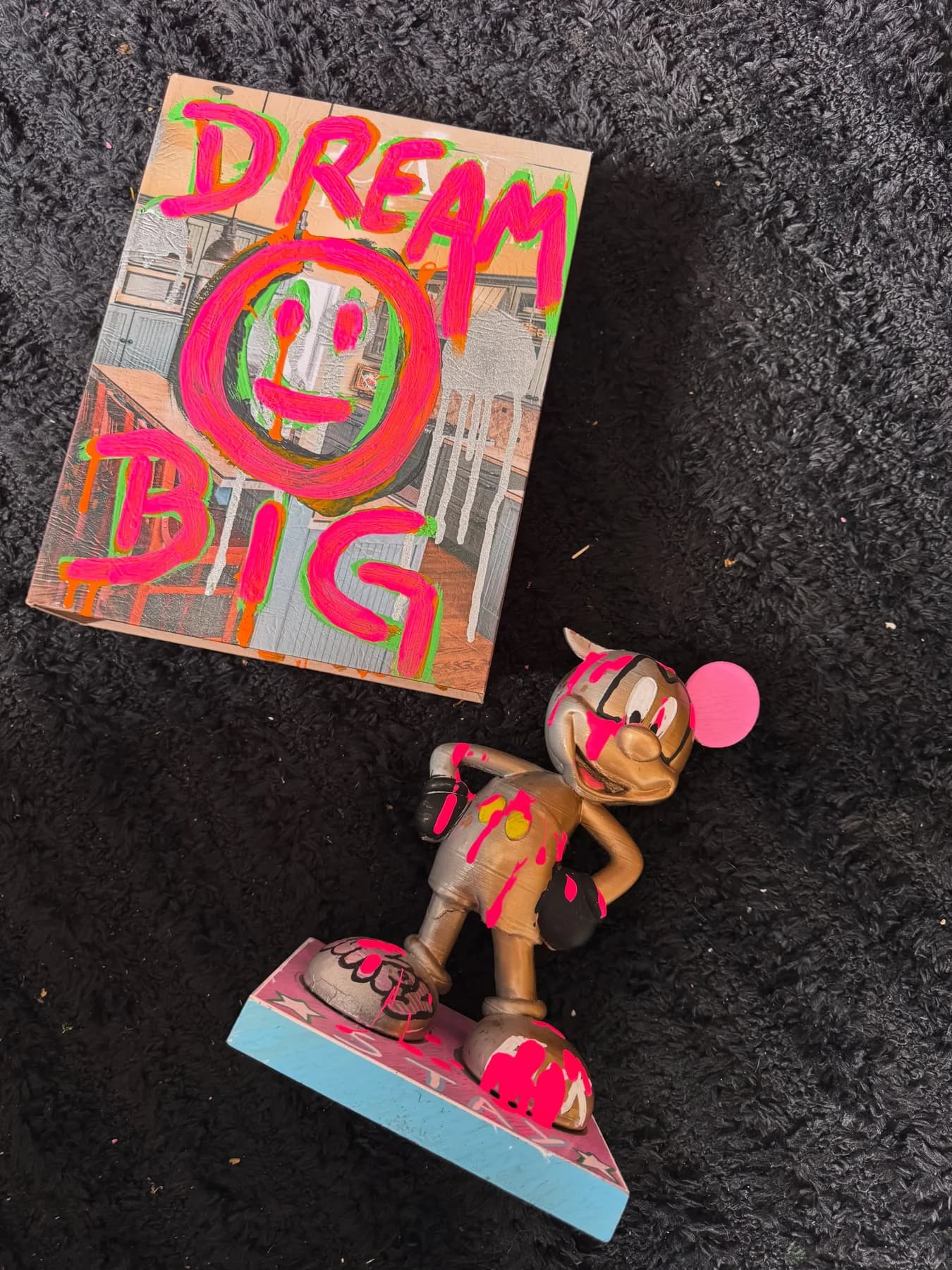 Quadro pequeno em rosa e verde neon com um rosto sorridente e a frase dream big