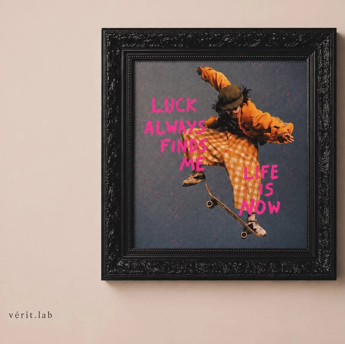 Quadro de moldura preta com um skatista de roupa laranja no ar e as frases luck always finds me e life is now em rosa